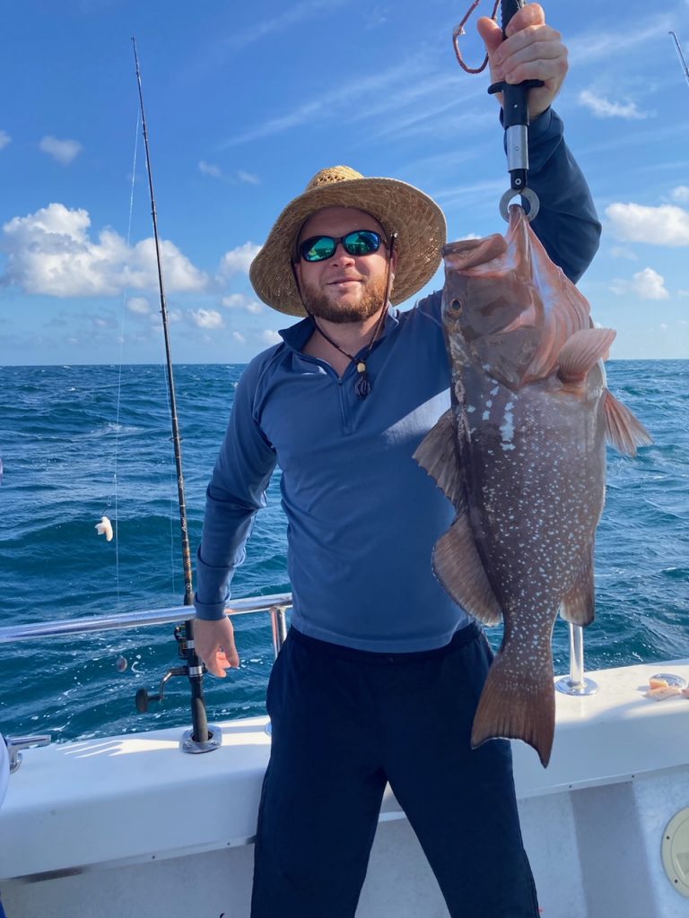Fisherman onboard A and B Charters holding a grouper